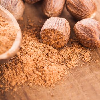 Ground nutmeg spice in the wooden spoon closeup