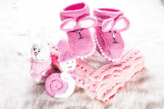 Knitted pink baby booties, toys, blanket for little girl