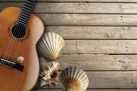 Acoustic brown guitar with four sea shells on beach wooden floor over summer sand