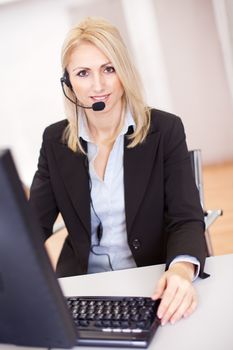 Beautiful call center operator talking over the phone in the office