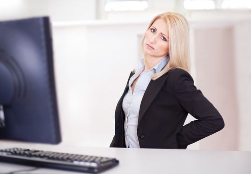 Business women having back pain at computer workplace