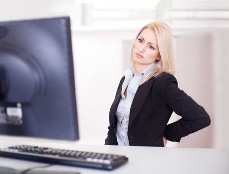 Business women having back pain at computer workplace