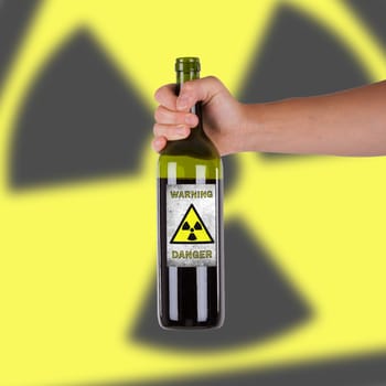 Hand holding a bottle with a warning, radioactive