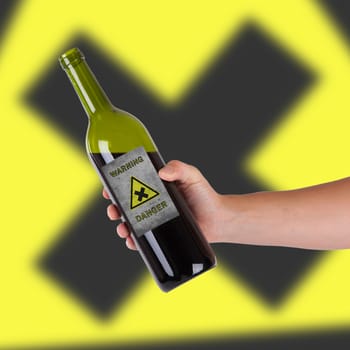 Hand holding a bottle with a warning, danger