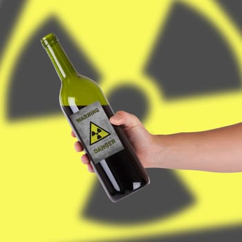 Hand holding a bottle with a warning, radioactive