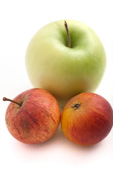 Juicy fresh small red apples and a single large green one arranged together on a white background for a healthy diet