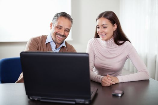 Two business colleagues looking at laptop and smiling.
