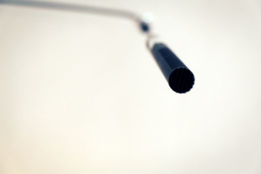 Condenser microphone hanging from the ceiling. Very low angle view. Narrow depth of field.