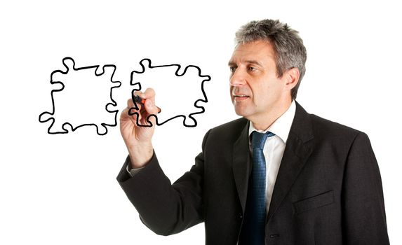 Businessman drawing jigsaw puzzle pieces. Isolated on white