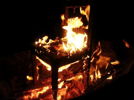 Wood chair burning inside bonfire.