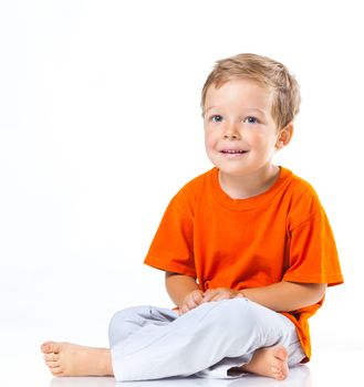 Adorable happy boy sitting on the floor in studio. Isolated of white background.