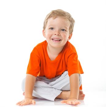 Adorable happy boy sitting on the floor in studio. Isolated of white background.