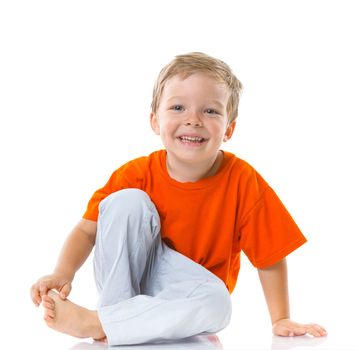 Adorable happy boy sitting on the floor in studio. Isolated of white background.