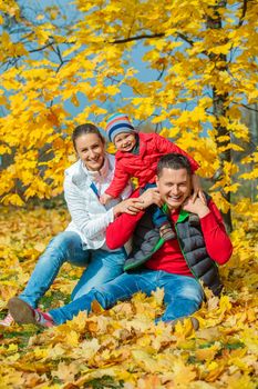 Happy family with baby boy at beautiful autumn park