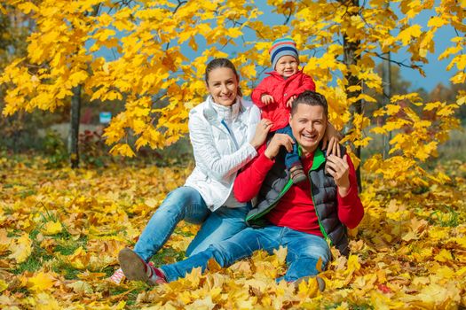Happy family with baby boy at beautiful autumn park