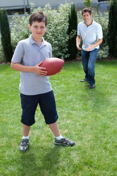 Cute little boy playing american football with his father