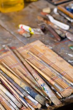 Messy atelier table with many  paintbrushes and other stuff