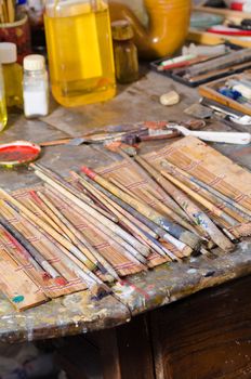 Many paintbrushes on a messy atelier table