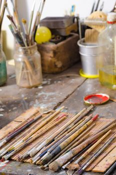 Many paintbrushes on a messy atelier table