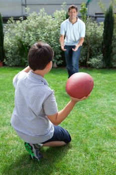 Little kid throwing football to his father in backyard