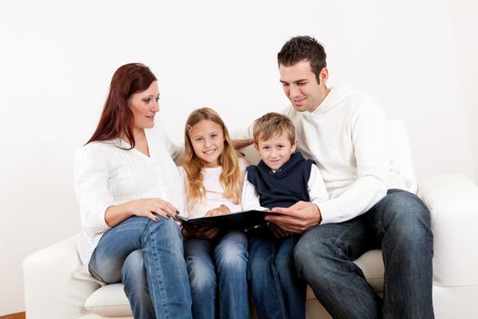 Hapy young family watching photo album at home