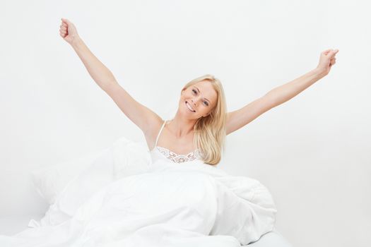 Young happy smiling woman waking up at bedroom
