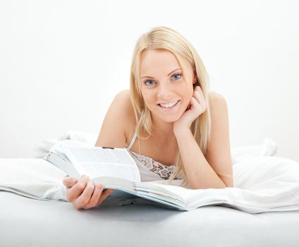 Young beautiful woman reading book in bed at home