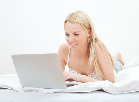 Young beautiful woman using laptop in bed at home