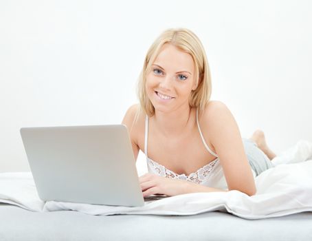 Young beautiful woman using laptop in bed at home