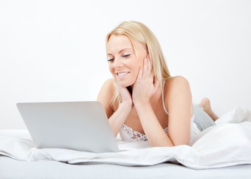 Young beautiful woman using laptop in bed at home