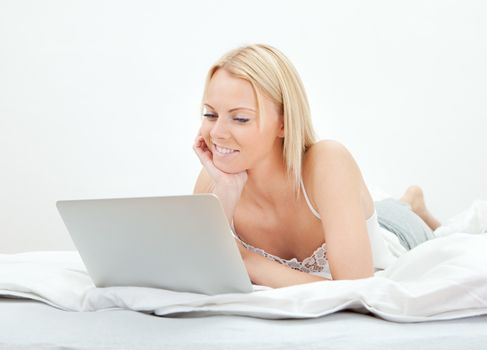 Young beautiful woman using laptop in bed at home