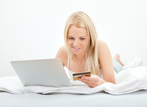 Young beautiful woman shopping using laptop in bed