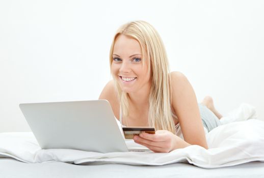 Young beautiful woman shopping using laptop in bed