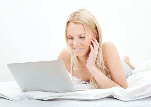 Young beautiful woman using laptop in bed at home