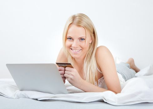 Young beautiful woman shopping using laptop in bed