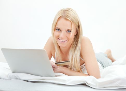 Young beautiful woman shopping using laptop in bed