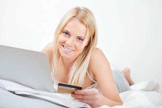 Young beautiful woman shopping using laptop in bed