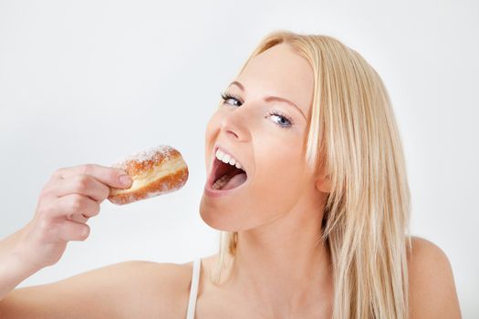 Beautiful woman eating tasty donut in bed