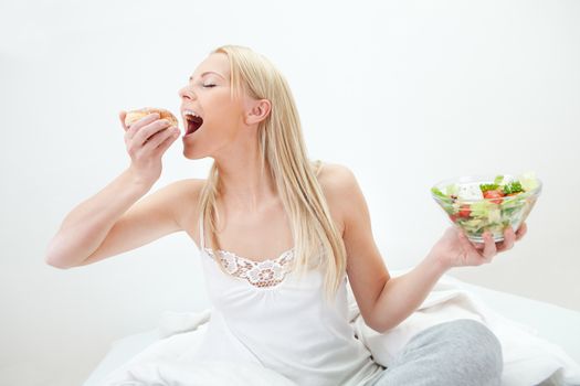 Tempted young woman making a choice between salad and donut