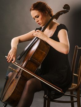 Photo of a beautiful female musician playing a cello.

