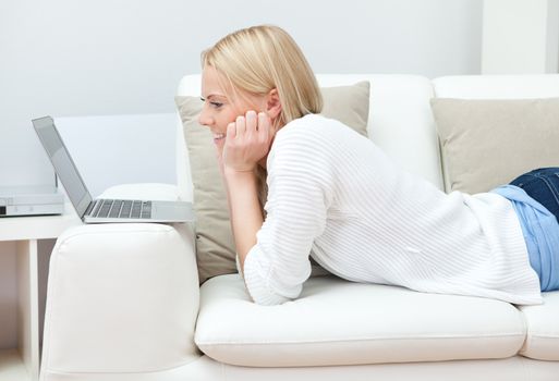 Beautiful woman working on computer sitting in sofa