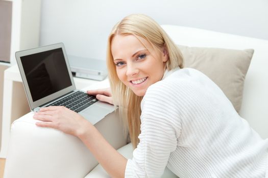Beautiful woman working on computer sitting in sofa