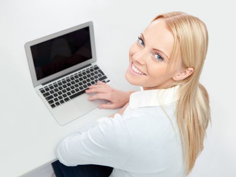 Beautiful woman working on laptop at the desk. Isolated on white