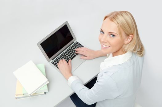 Beautiful student girl studying with laptop at the desk. Isolated on white