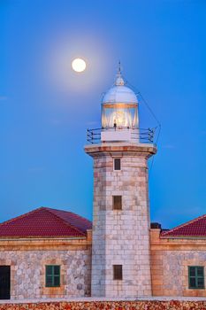 Ciutadella Menorca Punta Nati lighthouse with moon shining in sky