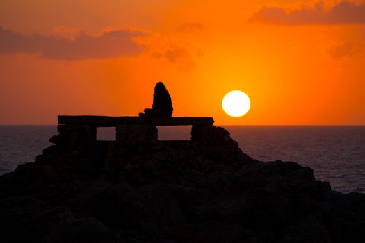 Ciutadella Menorca at Punta Nati orange sunset with girl backlight