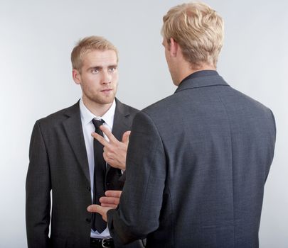 two you businessmen standing, discussing, arguing - isolated on light gray