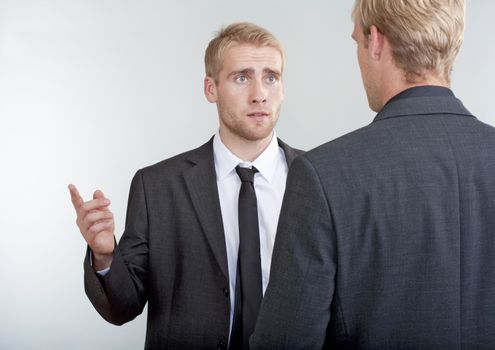 two you businessmen standing, discussing, arguing - isolated on light gray