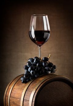 Wine goblet with wooden barrel and grape