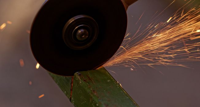 Metal sawing with hand grinder. Sparks while grinding iron.